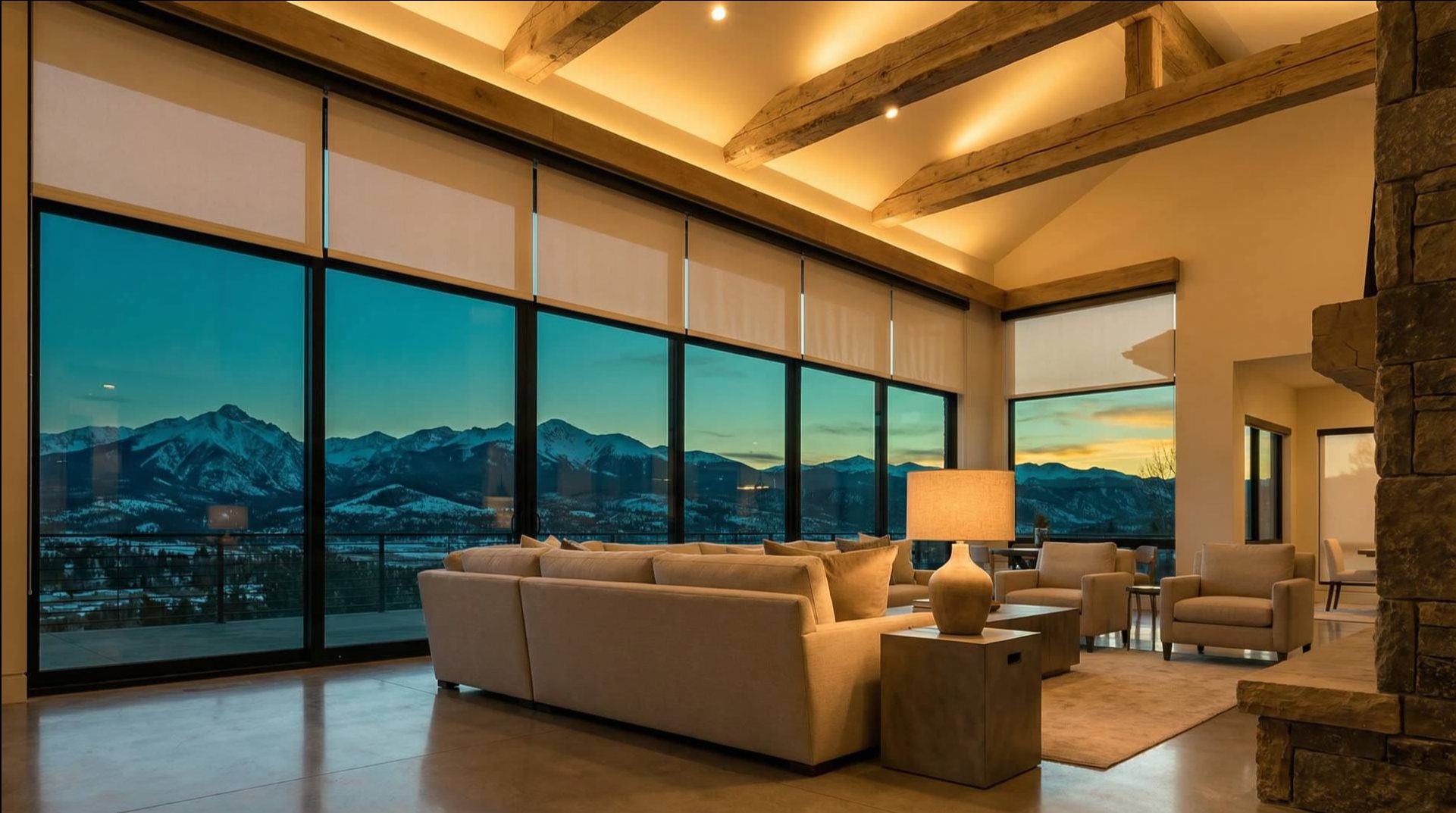 Luxury Colorado mountain home great room with motorized roller shades, cove lighting, and panoramic mountain views at sunset — installed by InVision Communications